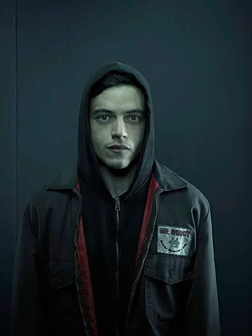 Retrato de Elliot Alderson (Rami Malek) de Mr. Robot, usando su icónica sudadera negra con la capucha puesta y una chaqueta oscura con el parche 'Mr. Robot' en el pecho, sobre un fondo oscuro paranoico.